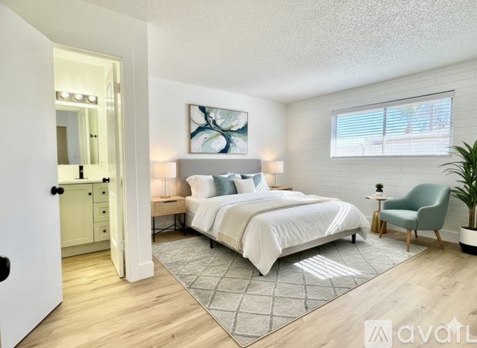 A bedroom with a large bed, a chair, and a painting on the wall.