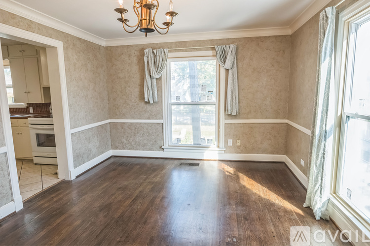 A room with a chandelier and a window with curtains.