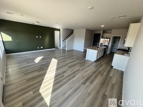 A spacious room with wooden flooring and a staircase leading to another level.