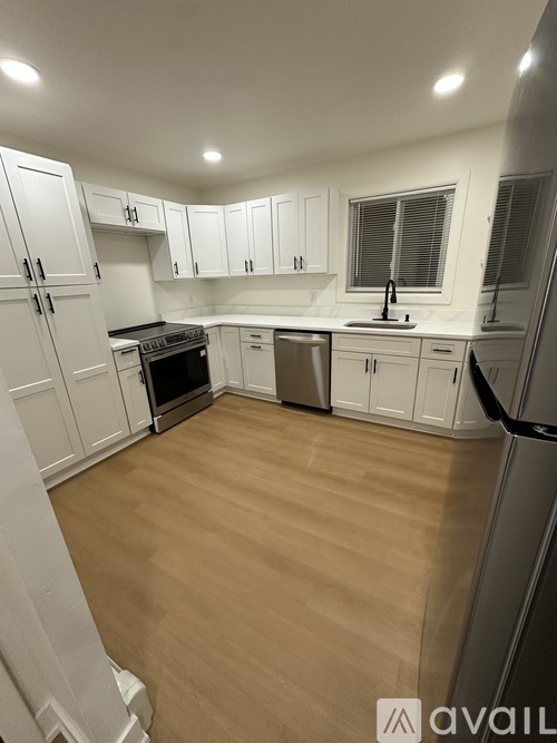 A kitchen with white cabinets and a wooden floor.