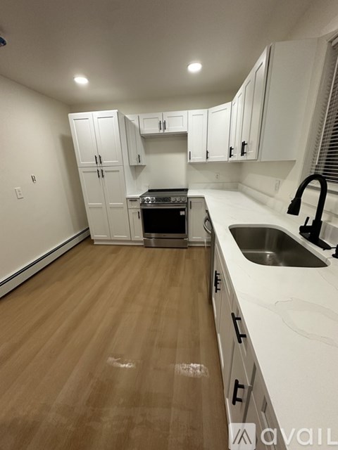 A kitchen with white cabinets and a wooden floor.