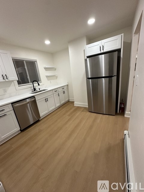 A kitchen with a stainless steel refrigerator and wooden flooring.