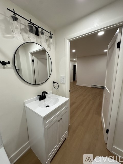 A bathroom with a white sink and a round mirror.