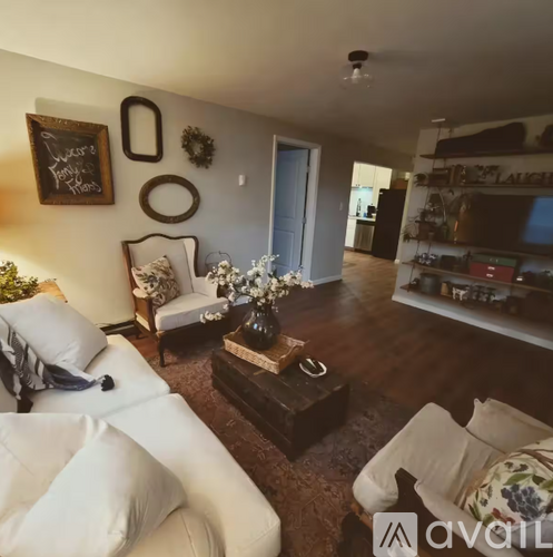 A living room with a white couch and a coffee table with a vase of flowers on it.