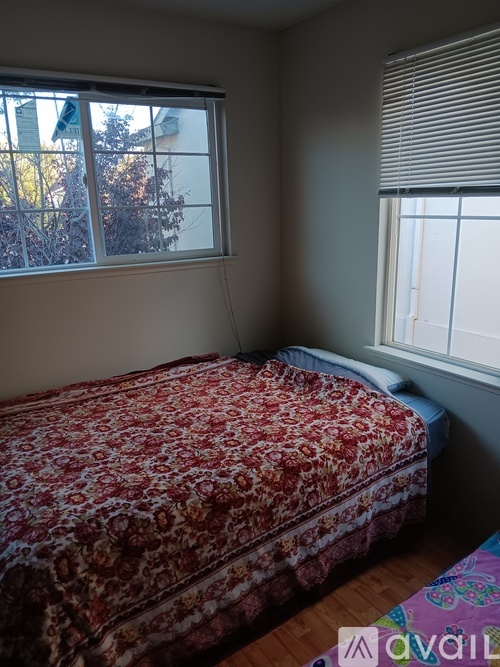 A bedroom with a bed covered in a red and gold patterned bedspread.