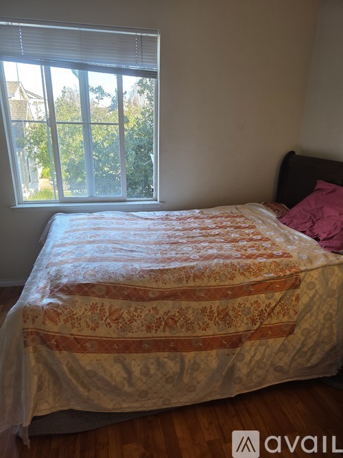 A bed with a floral patterned cover sits in a room with a window.