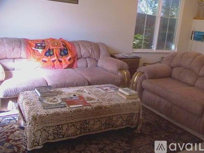 A living room with a couch, ottoman, and a window.