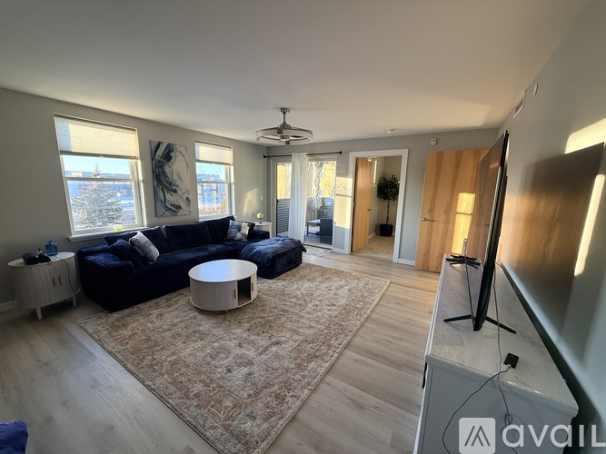 A living room with a black sofa and a rug.