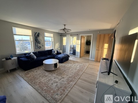 A living room with a black sofa and a rug.