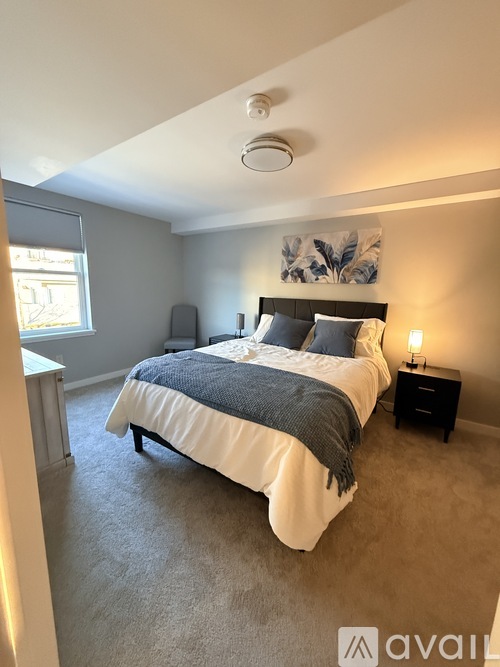 A bedroom with a bed, nightstand, and window.