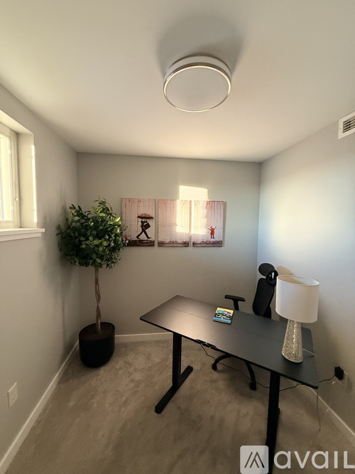 A room with a table, lamp, and plant.