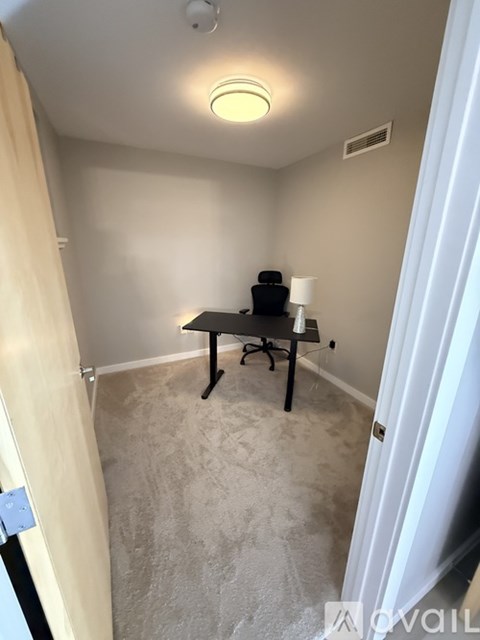 A room with a table, lamp, and plant.