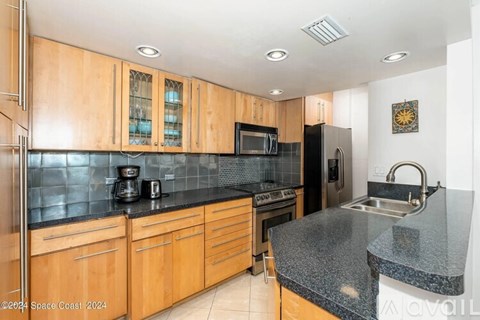 A kitchen with wooden cabinets and black countertops.