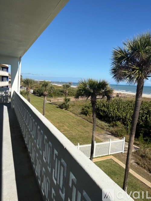 A balcony with a view of the beach and palm trees.