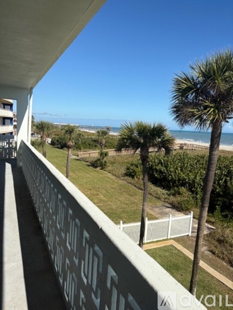 A balcony with a view of the beach and palm trees.