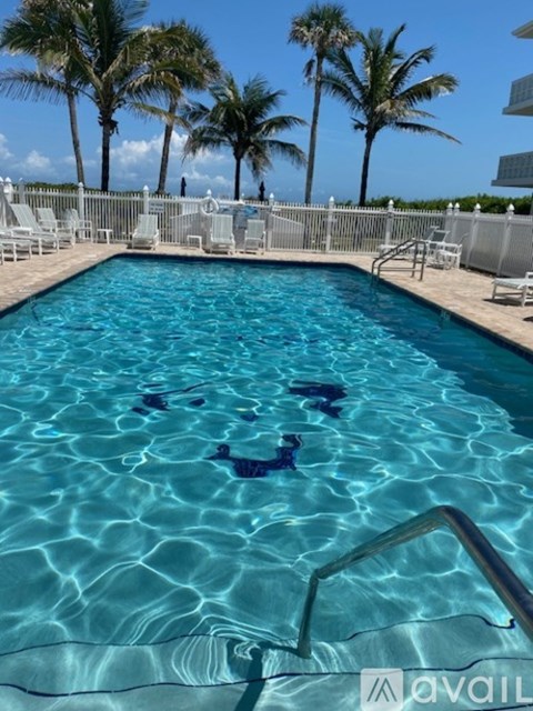 A swimming pool with a metal ladder and palm trees in the background.
