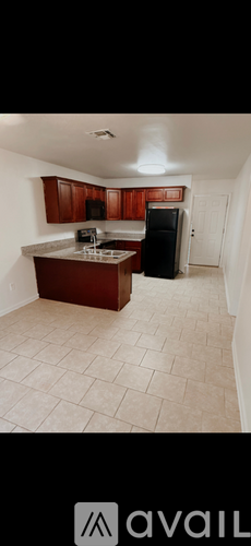 A kitchen with brown cabinets and a black refrigerator.