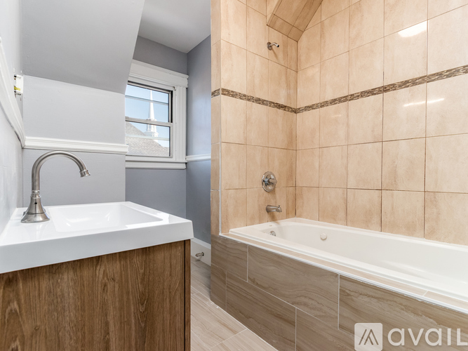A bathroom with a tub, sink, and window.