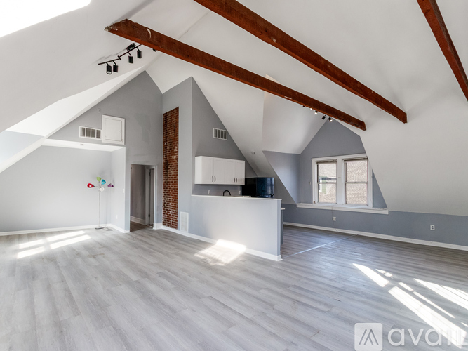 A spacious room with wooden beams on the ceiling and a white cabinet.