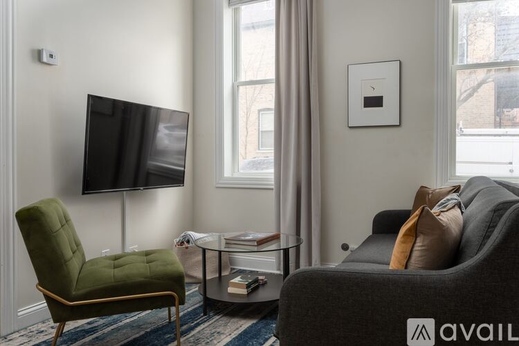 A living room with a green chair, a black couch, and a flat screen TV.