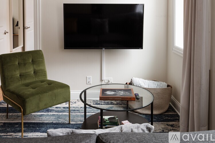 A green chair sits in front of a black television in a living room.