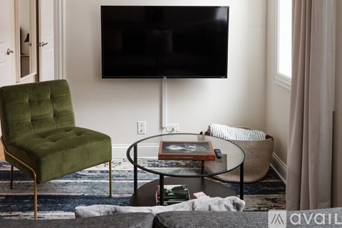 A green chair sits in front of a black television in a living room.