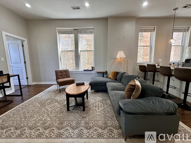 A living room with a grey couch and a patterned rug.