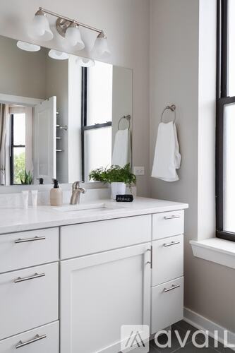 A white bathroom with a sink, mirror, and a window.