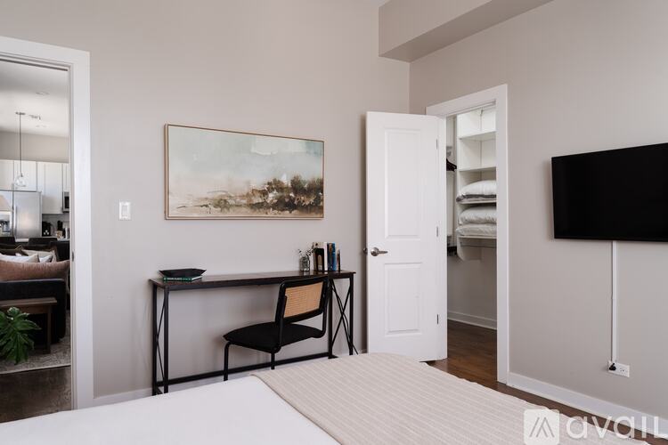 A room with a desk and chair, a painting on the wall, and a door leading to another room.