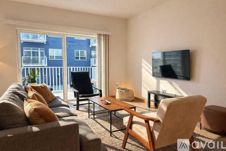 A living room with a grey couch, a wooden coffee table, and a flat screen TV mounted on the wall.