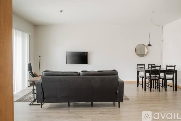 A living room with a black sofa and a television mounted on the wall.
