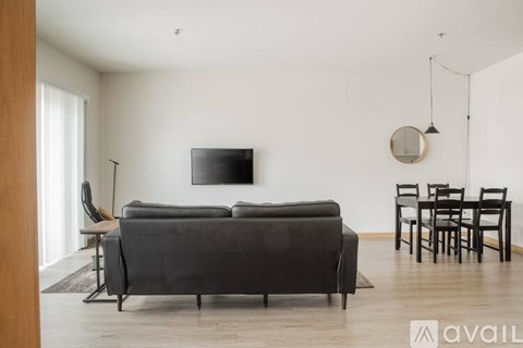 A living room with a black sofa and a television mounted on the wall.