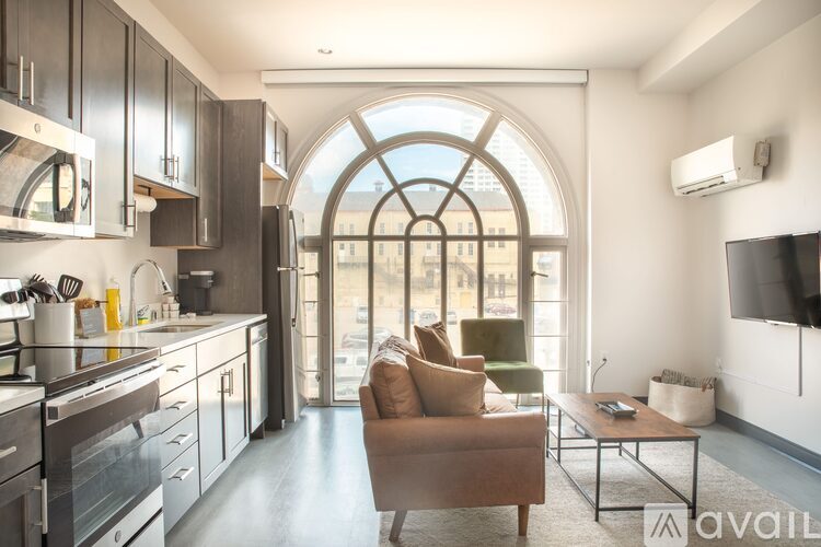 A modern kitchen with a large window and a seating area.