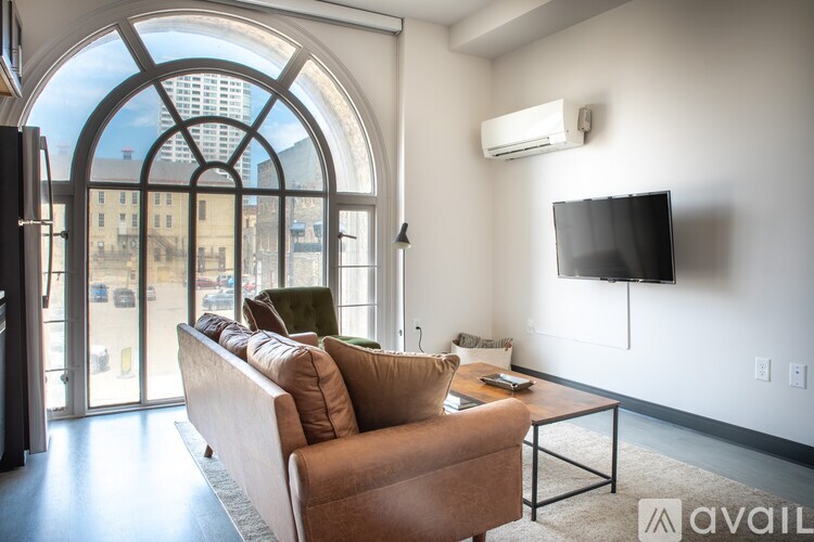 A living room with a couch, a coffee table, and a television mounted on the wall.