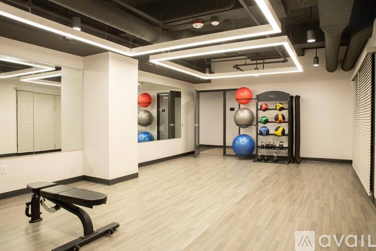 A gym room with a bench, exercise balls, and a rack of equipment.