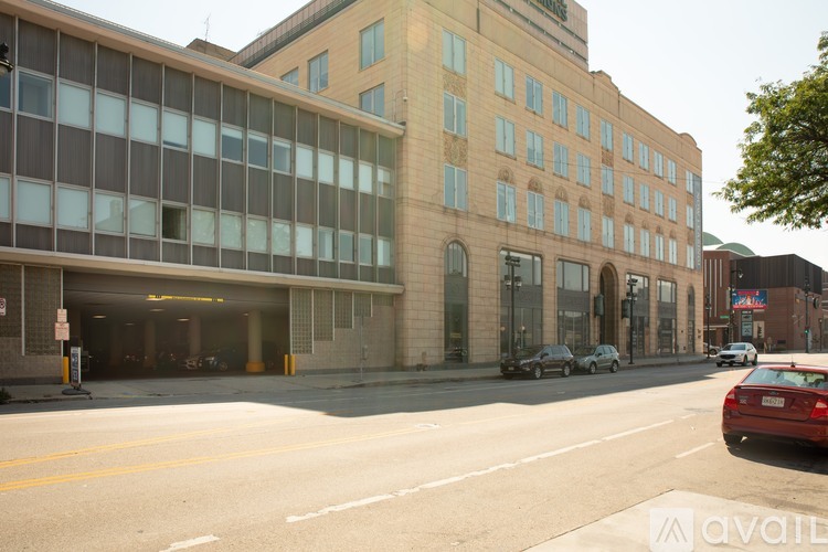 A red car is parked on the side of the street in front of a building.