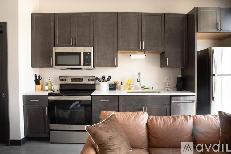 A kitchen with brown cabinets and a brown couch.