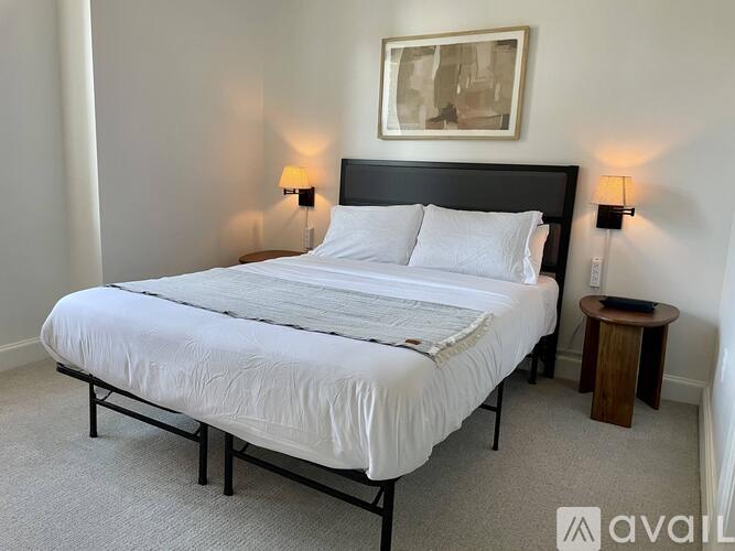 A bedroom with a large bed and a small table beside it.