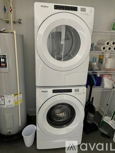 Two white Whirlpool washing machines stacked on top of each other in a laundry room.