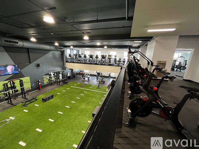 A gym with a green artificial turf and exercise equipment.