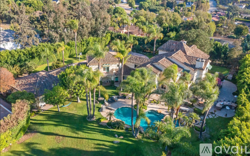 A large house with a pool surrounded by trees.