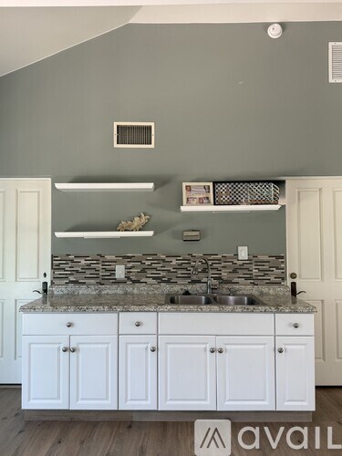 A kitchen with a granite countertop and white cabinets.
