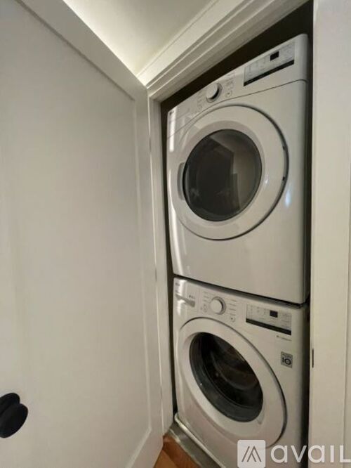 Two washing machines are stacked in a small space.