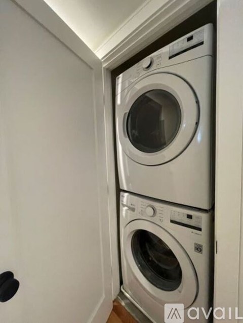 Two washing machines are stacked in a small space.