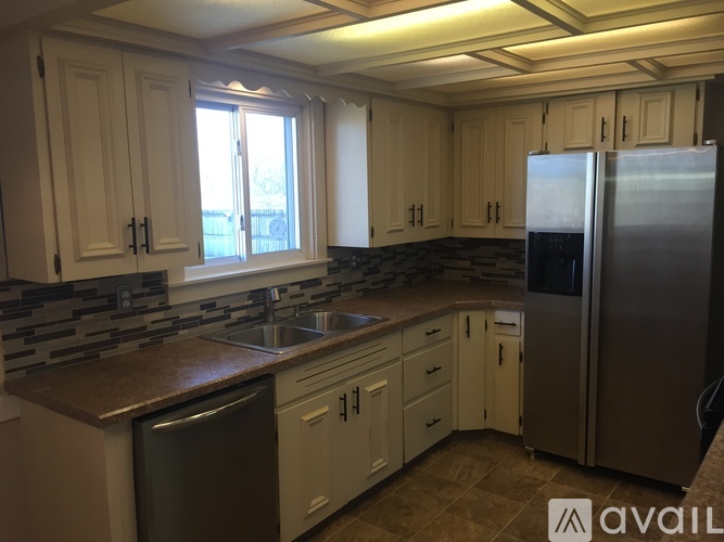 A kitchen with white cabinets and a refrigerator.
