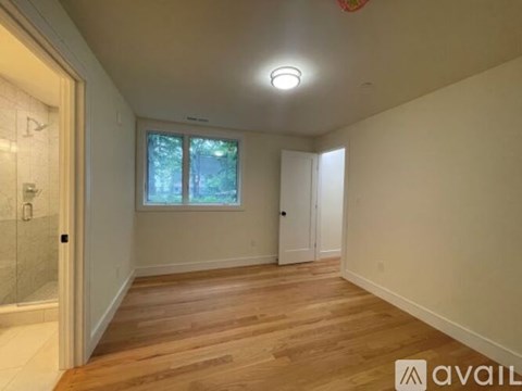 A room with wooden floors and a window with a view of trees.