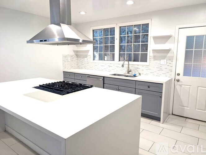 A modern kitchen with a white island and stainless steel appliances.