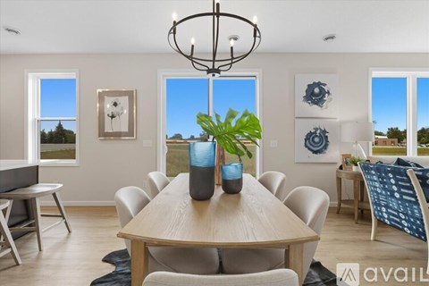 A dining room with a wooden table and chairs, a potted plant, and pictures on the wall.