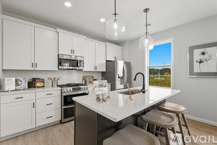 A kitchen with white cabinets and a large island with stools.