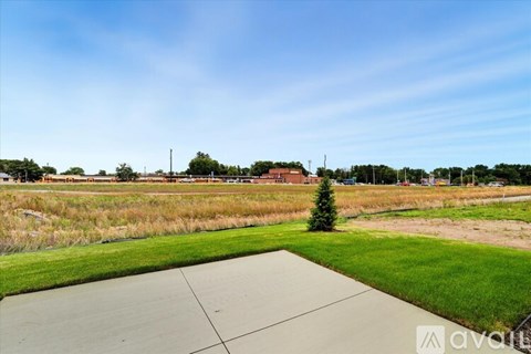 A large open field with a small tree and a building in the distance.